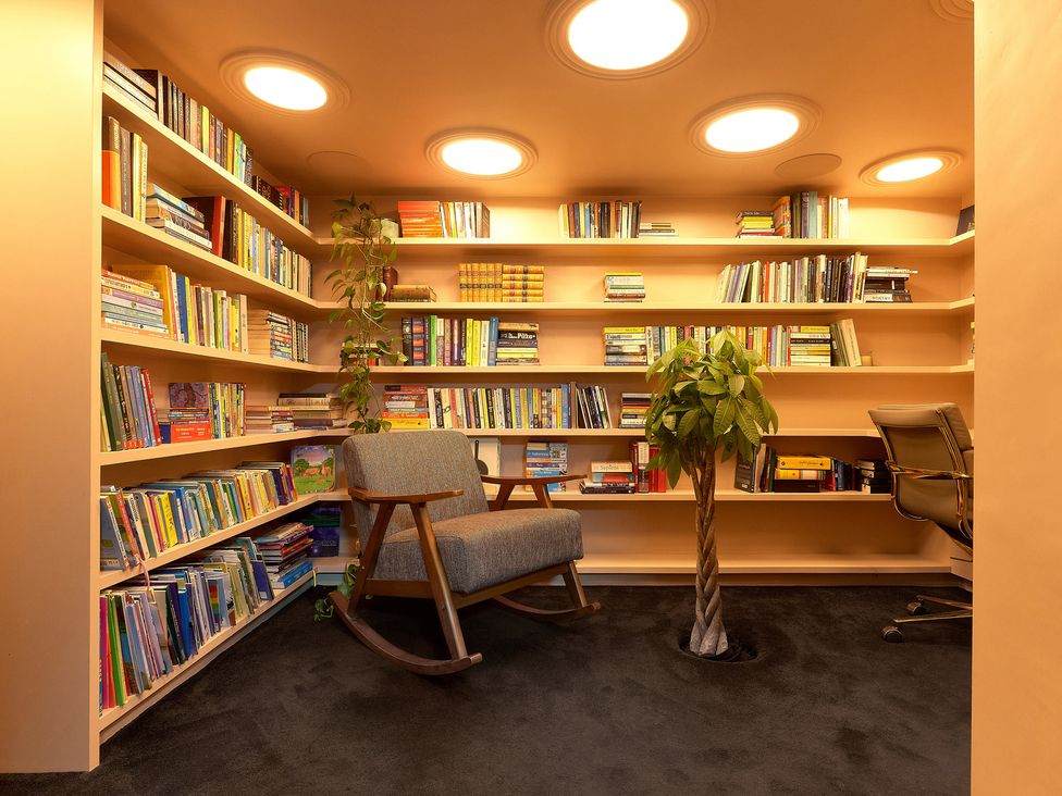 A study room with bookshelves and a rocking chair at Providence Cottage Trellech