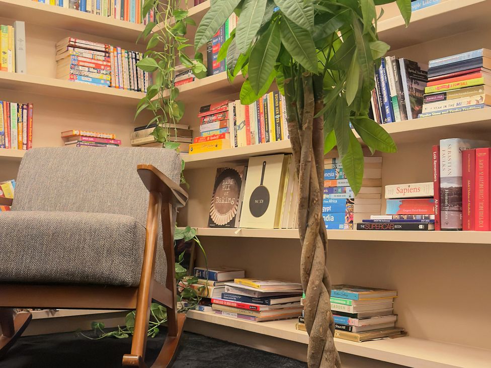 A reading room with a rocking chair and books on a shelf at Providence Cottage Trellech