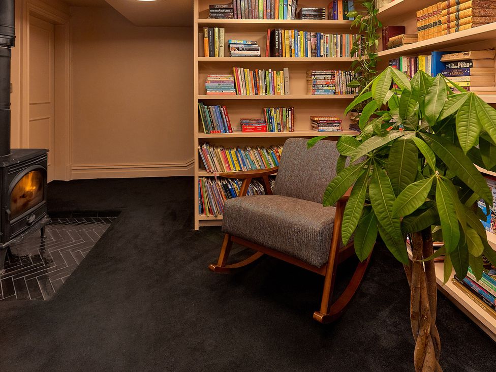 A snug area with a bookshelf and a rocking chair at Providence Cottage Trellech