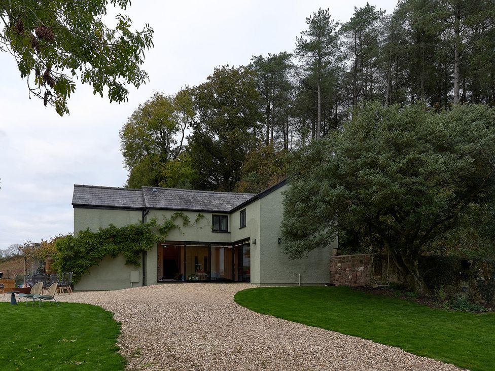 A house with a gravel driveway and trees at Providence Cottage in Trellech
