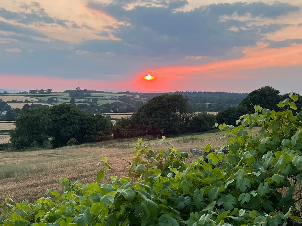 A sunset over fields and trees at Providence Cottage in Trellech