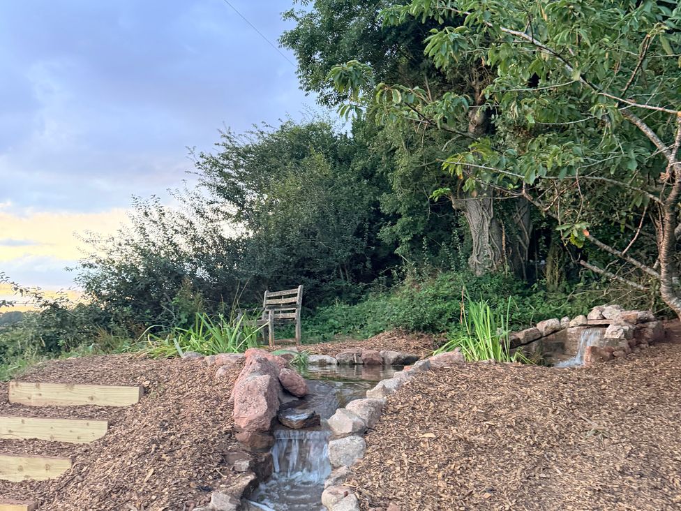 A garden with a water feature and a bench at Providence Cottage in Trellech