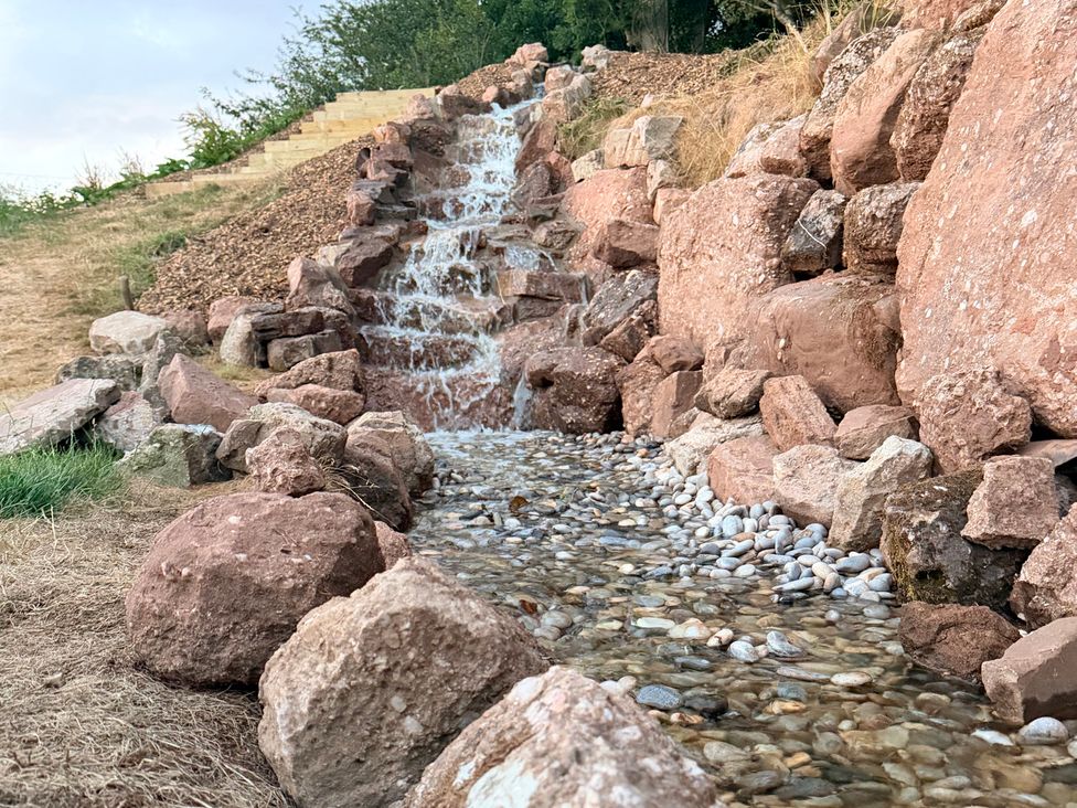 A waterfall and stream with rocks and pebbles at Providence Cottage in Trellech