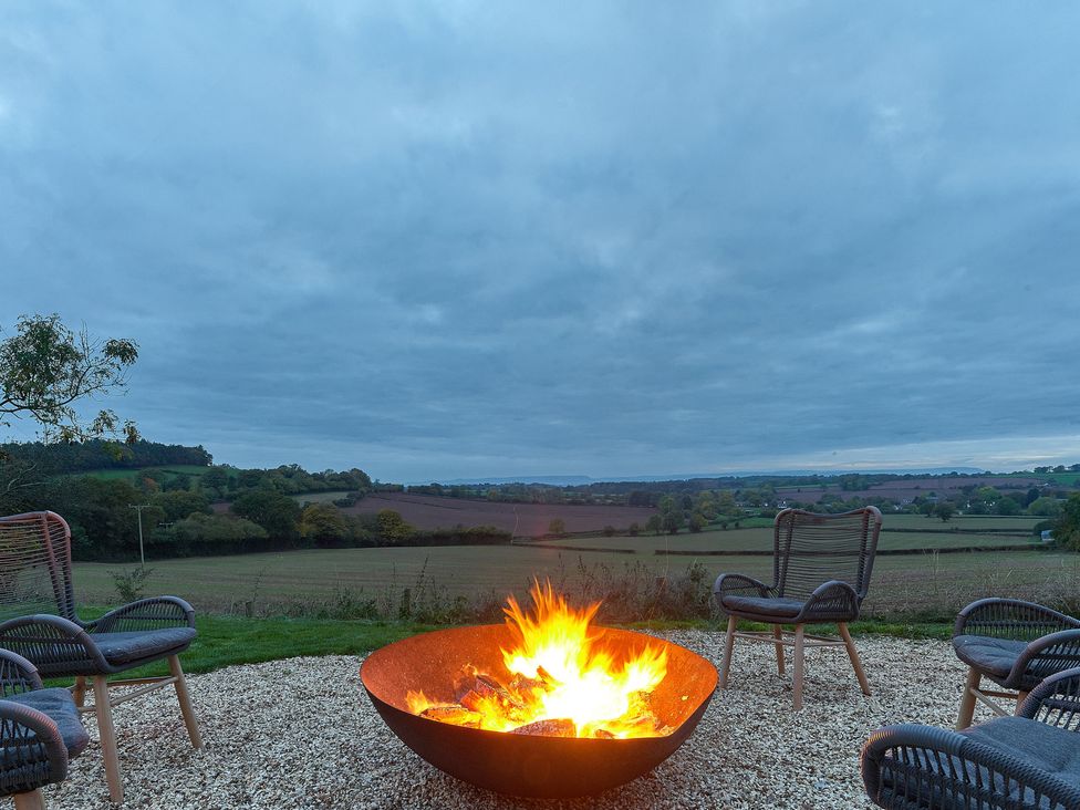 An outdoor area with a fire pit and chairs at Providence Cottage Trellech