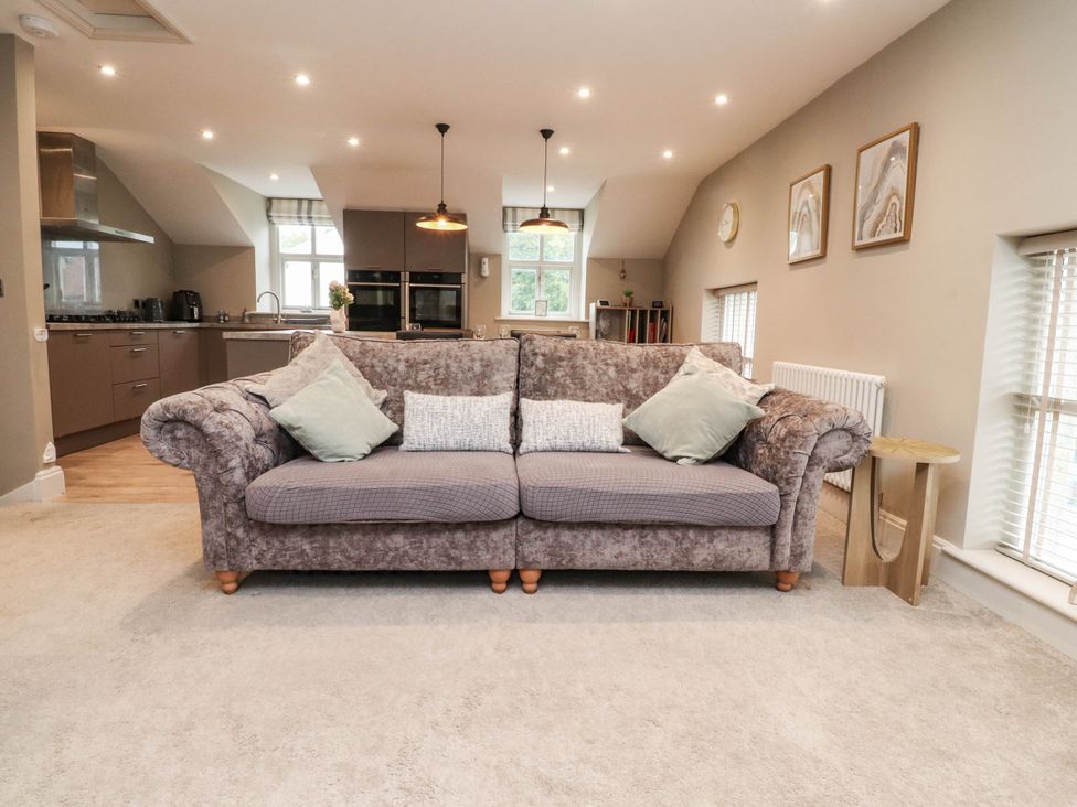 A living room with a sofa and kitchen in view at 4 Church Hall Mews in Garstang