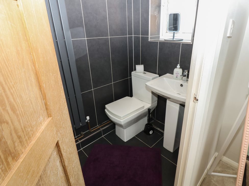 A bathroom with a toilet, sink, and a mirror at 4 Murrayfields, Newcastle upon Tyne