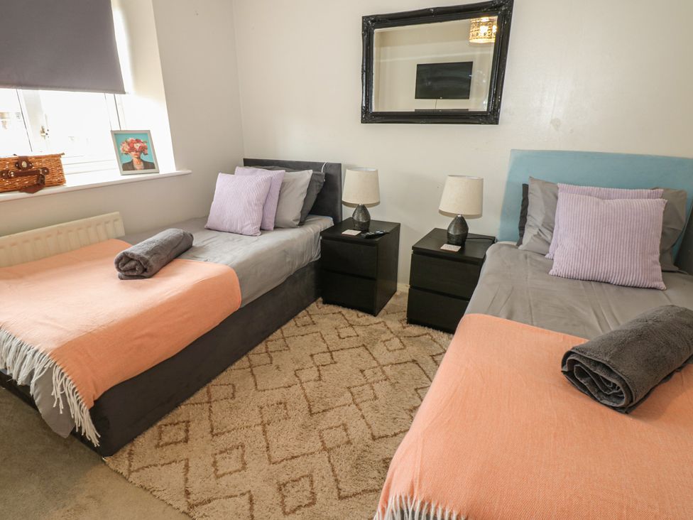 A bedroom with two beds and a mirror at 4 Murrayfields in Newcastle upon Tyne