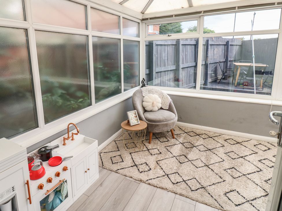 A conservatory with a chair and toy kitchen at 4 Murrayfields Newcastle upon Tyne