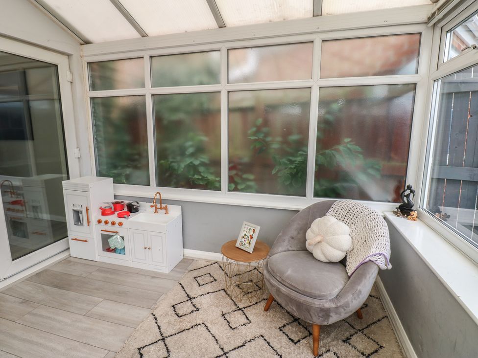 A conservatory with a child's kitchen set and an armchair at 4 Murrayfields Newcastle upon Tyne