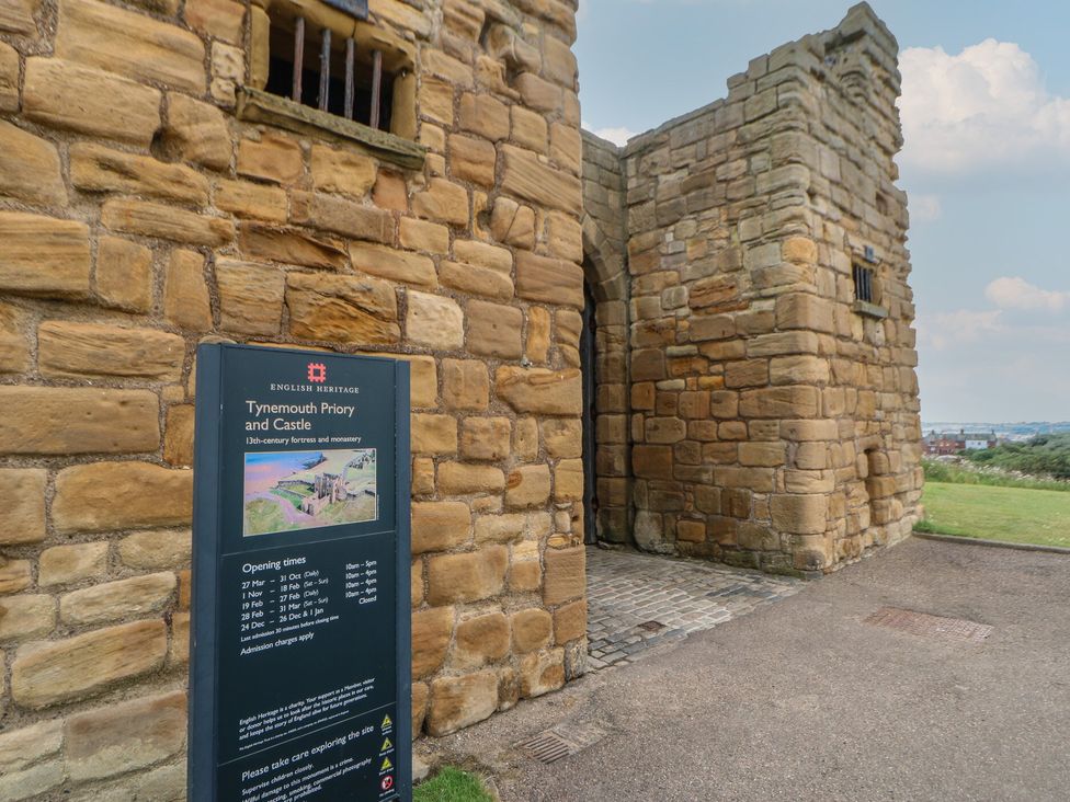 An entrance to Tynemouth Priory and Castle with information sign near the wall in Tynemouth