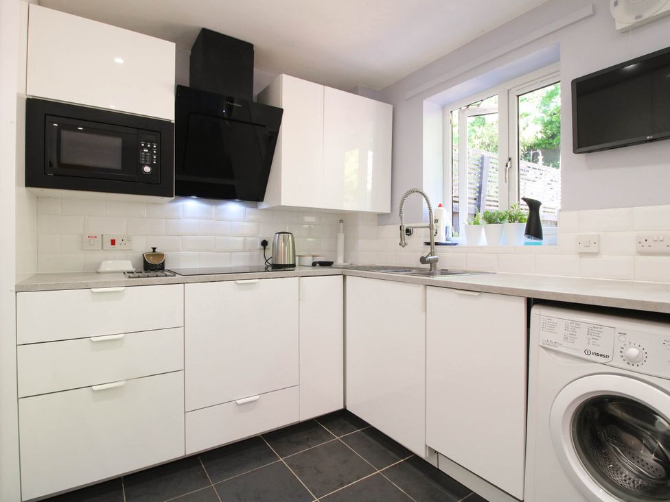 A kitchen with microwave, sink, and washing machine at Lilac Cottage in Ironbridge