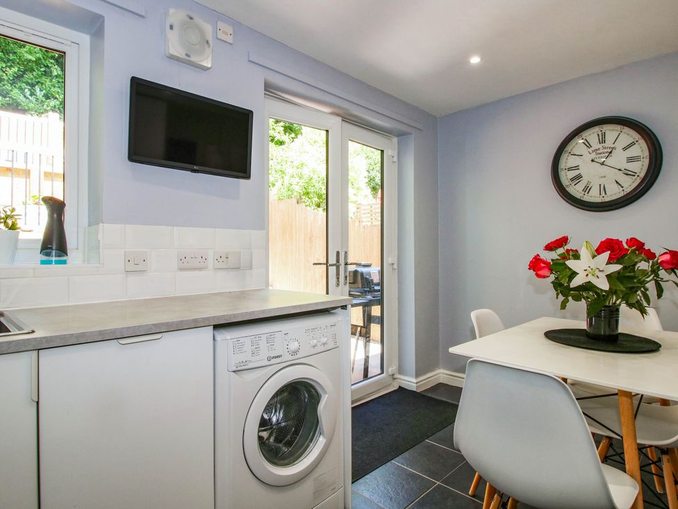 A kitchen with washing machine and dining table at Lilac Cottage in Ironbridge