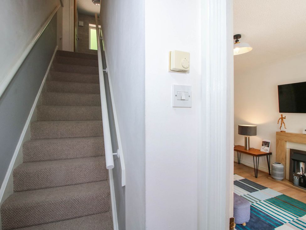 A staircase leading to a hallway with a light switch at Lilac Cottage Ironbridge