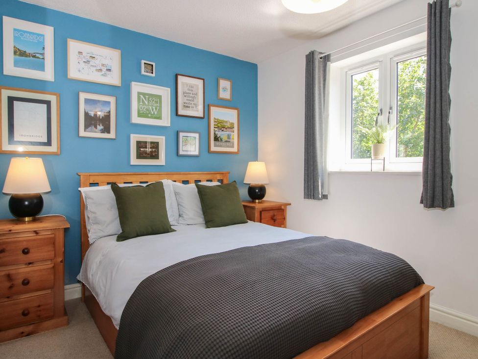 A bedroom with a bed and wall art at Lilac Cottage in Ironbridge