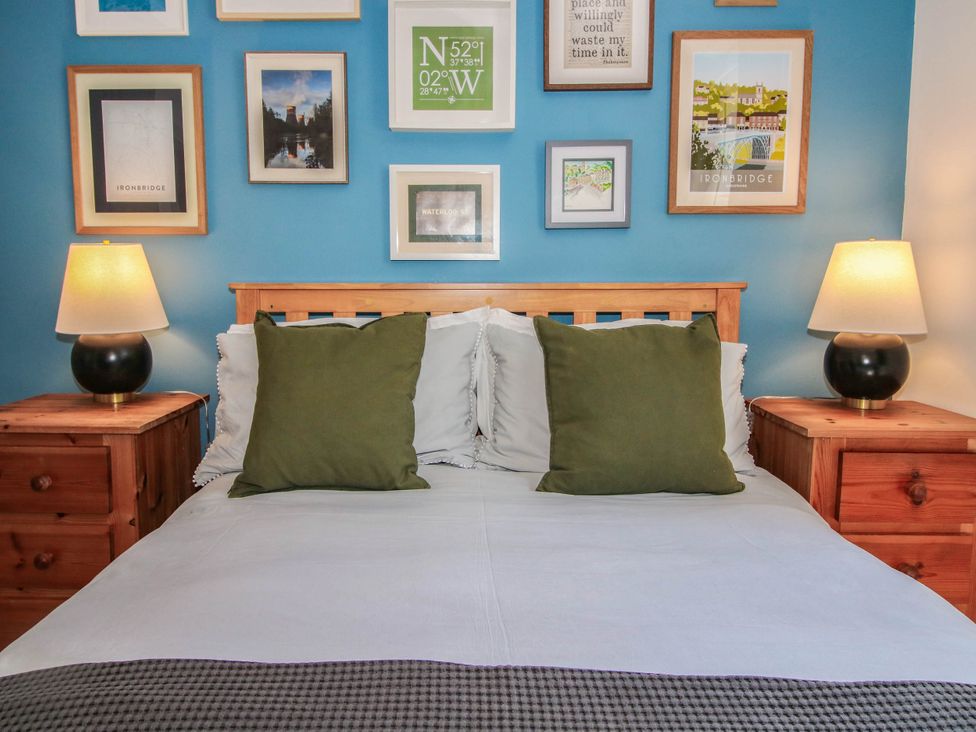 A bedroom with a bed and wall art at Lilac Cottage in Ironbridge