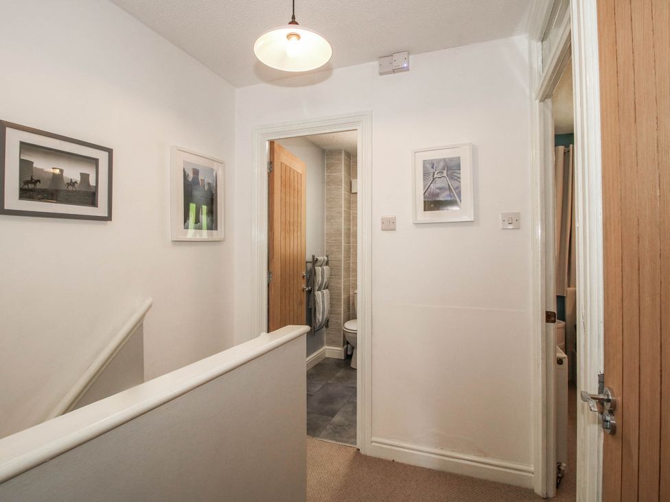 A hallway with a staircase and bathroom access at Lilac Cottage Ironbridge