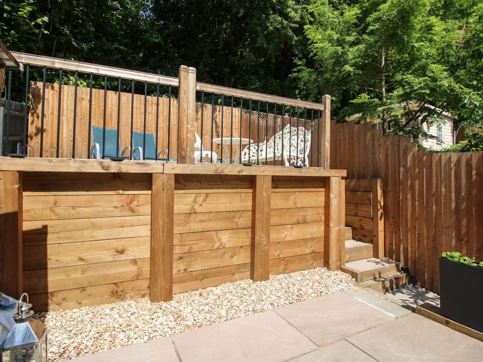 A garden with wooden decking, seating area and stone pathway at Lilac Cottage in Ironbridge
