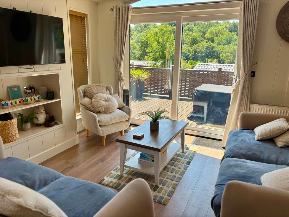 A living room with a television, sofa, and coffee table at Lakeside Retreat in Newton Abbot
