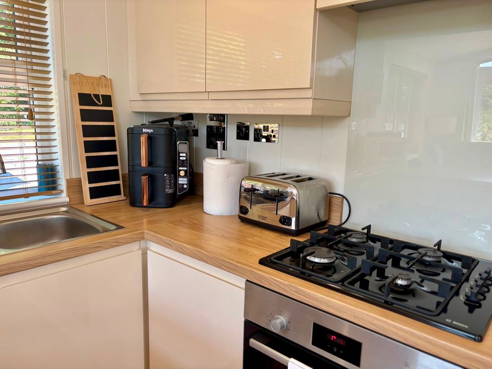 A kitchen with appliances including a sink, cooker, toaster, and coffee maker at Lakeside Retreat in Newton Abbot