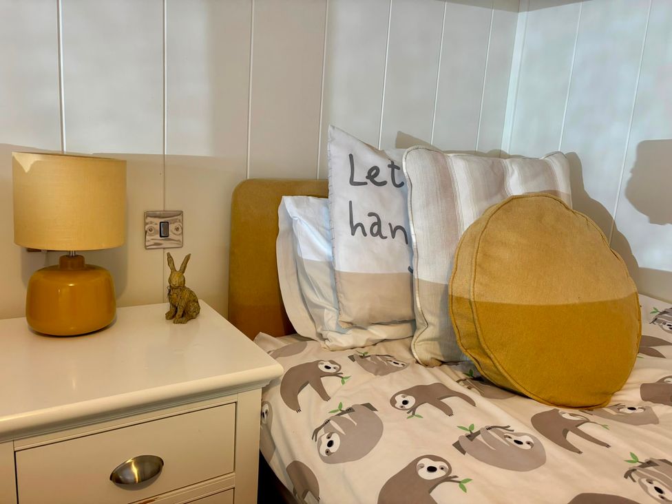 A bedroom with a lamp and pillows on a bed at Lakeside Retreat in Newton Abbot
