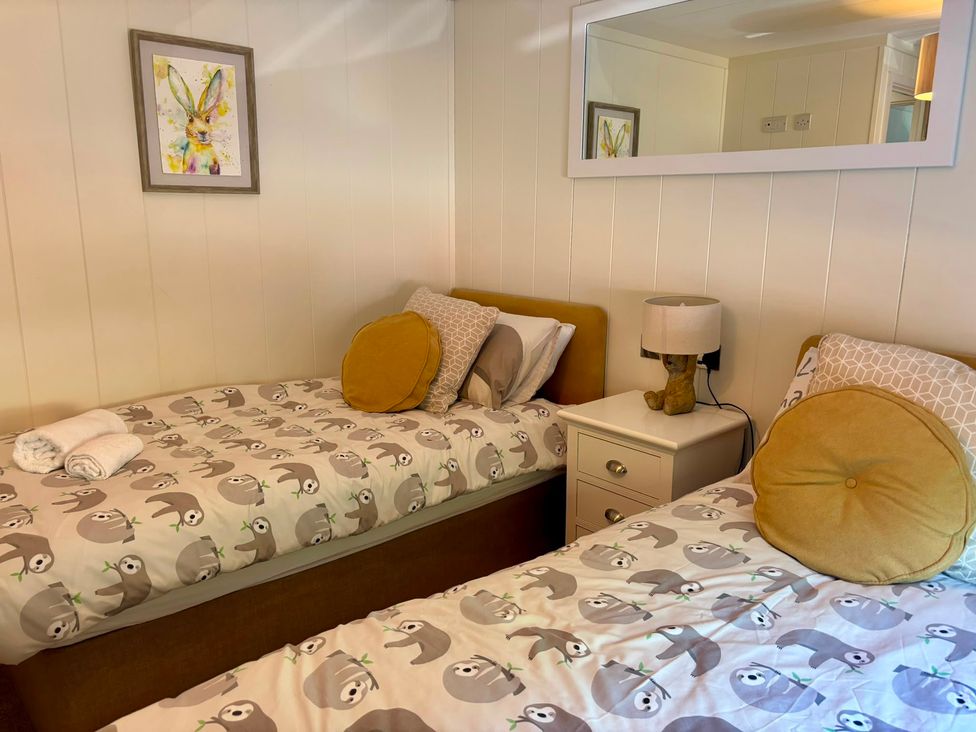 A bedroom with twin beds and a nightstand at Lakeside Retreat in Newton Abbot
