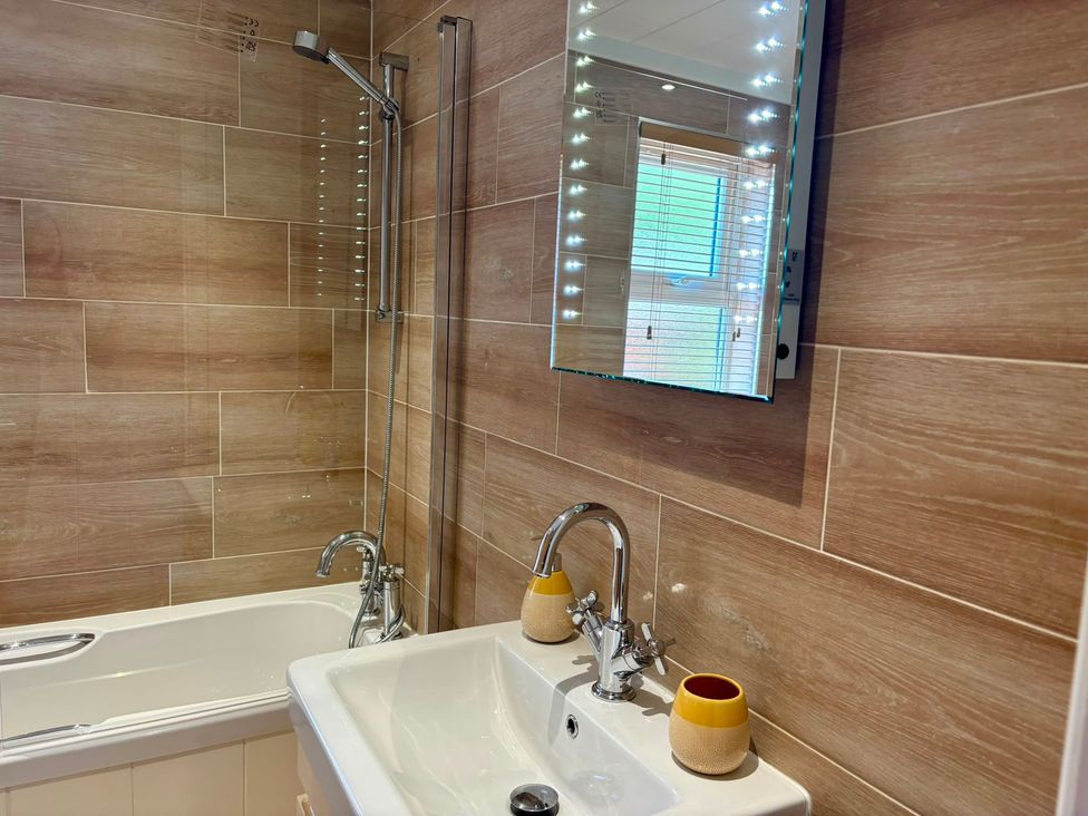 A bathroom with a bathtub, sink, and shower at Lakeside Retreat in Newton Abbot