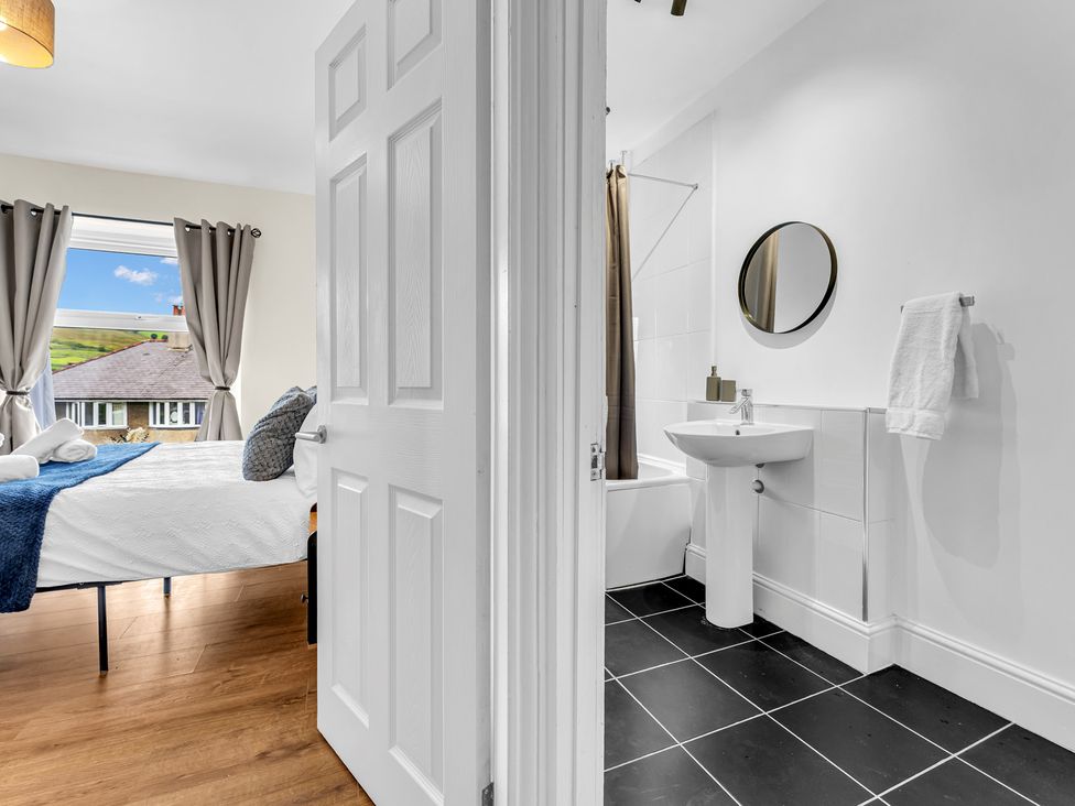 A bathroom with a sink and tub visible from a bedroom at Peak View Terrace