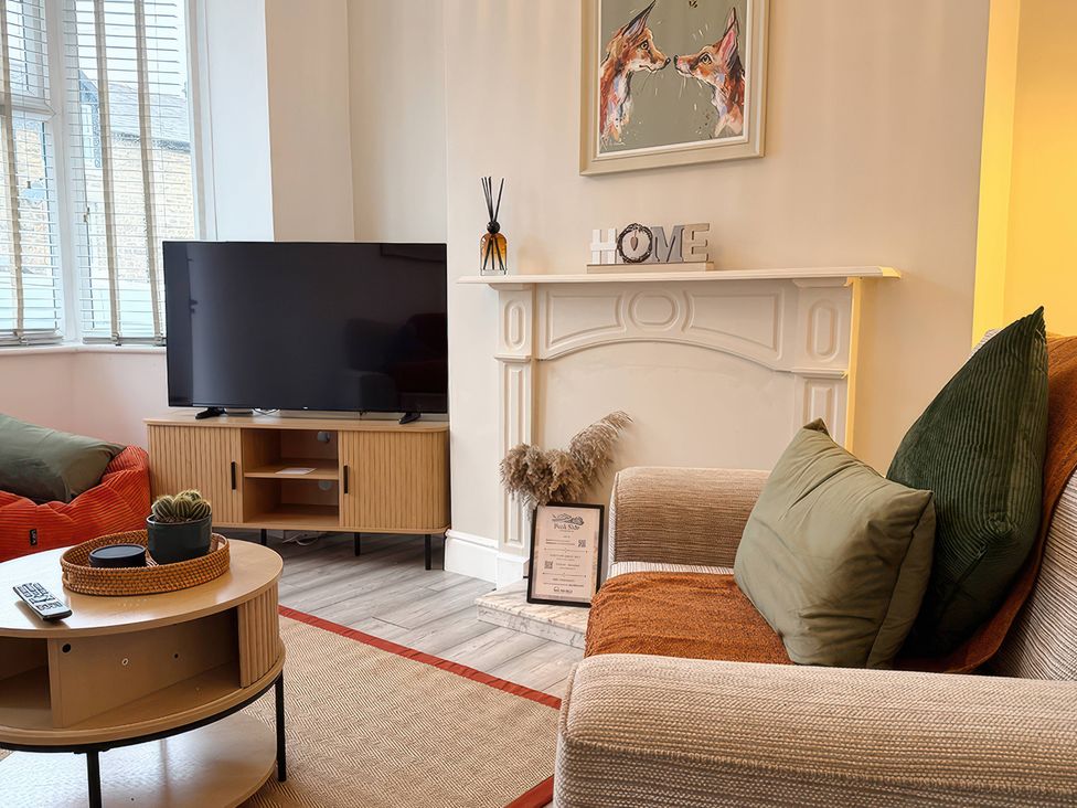 A living room with a television and sofa at Peak Side Terrace in Buxton