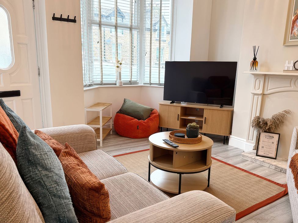 A living room with a television on a stand and a coffee table at Peak Side Terrace Buxton