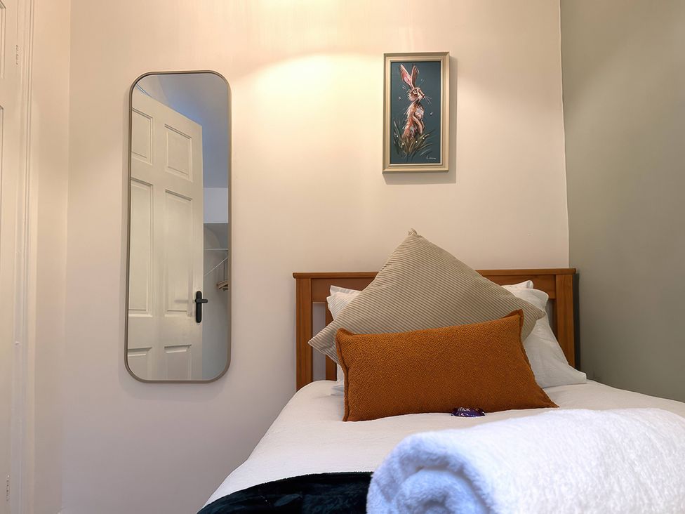 A bedroom with a bed, mirror, and wall art at Peak Side Terrace in Buxton