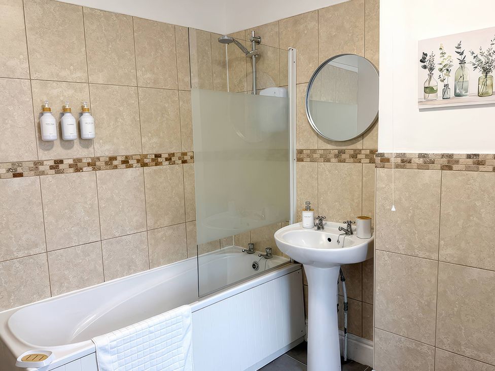 A bathroom with a sink, bathtub, shower, and wall decor at Peak Side Terrace, Buxton