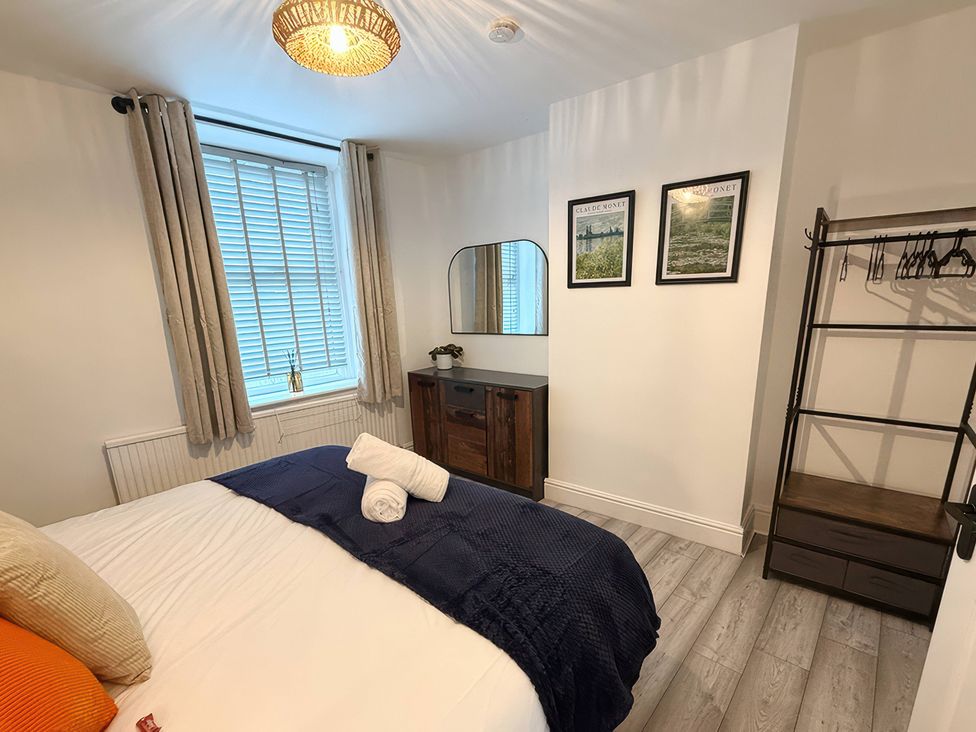 A bedroom with a bed, dresser, and clothes rack at Peak Side Terrace in Buxton