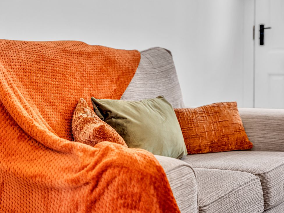 A sofa with cushions and a blanket at Peak Side Terrace Buxton