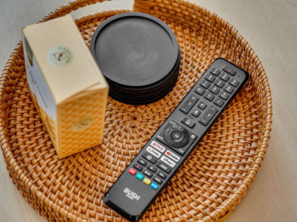 A remote control and coasters on a woven tray at Peak Side Terrace Buxton