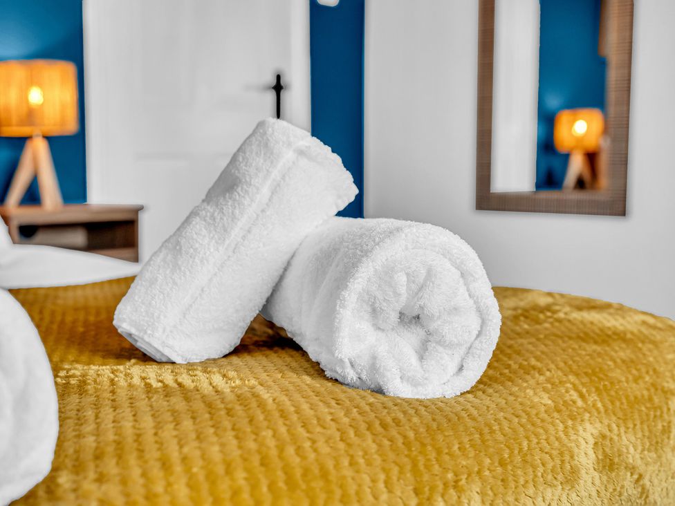 A bed with rolled towels and a lamp at Peak Side Terrace Buxton