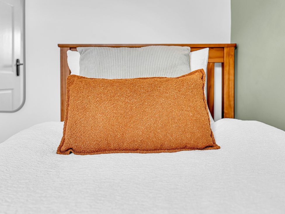 A bed with pillows and a door in Peak Side Terrace Buxton