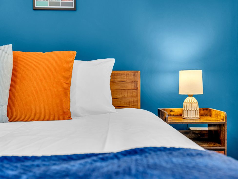 A bedroom with a bed and nightstand with a lamp at Peak Side Terrace in Buxton