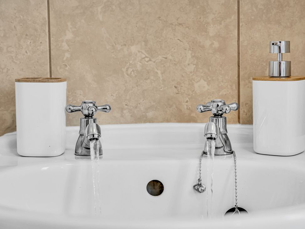 A sink with taps and containers at Peak Side Terrace in Buxton