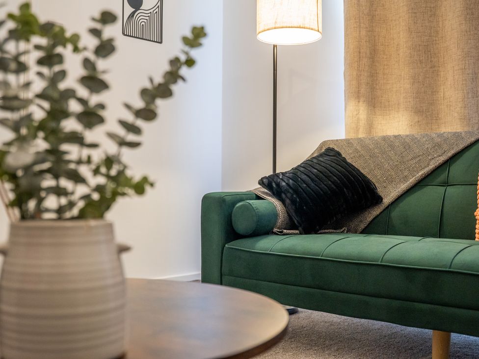 A living room with a green sofa and a lamp at Edison House Stafford