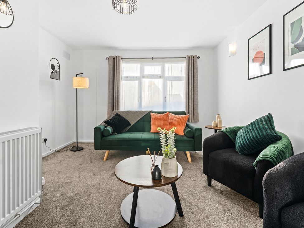 A living room with a green sofa and coffee table at Edison House Stafford