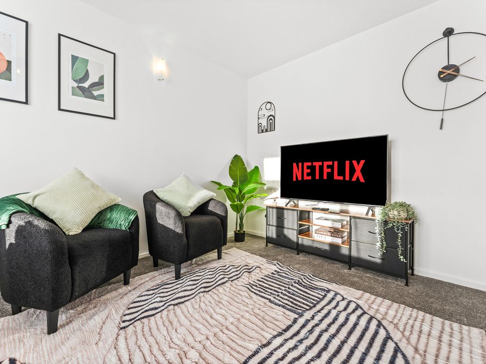 A living room with armchairs and a television at Edison House Stafford