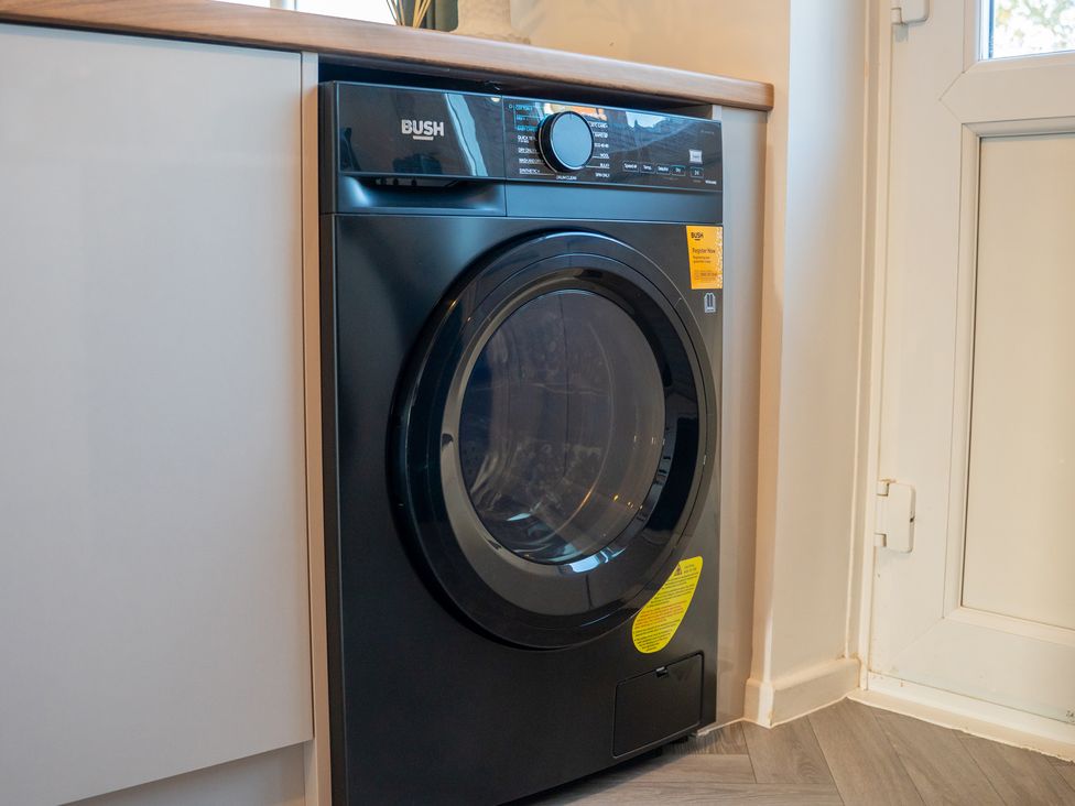 A washing machine next to a cabinet in a laundry room at Edison House Stafford