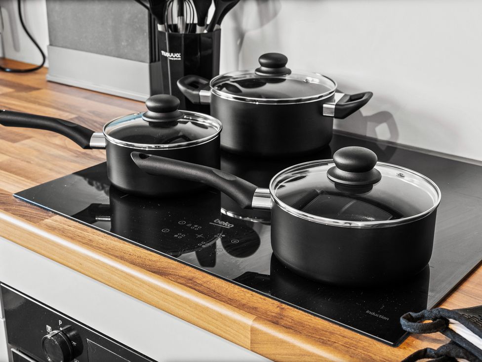 Three black cooking pots on an induction cooktop at Edison House Stafford