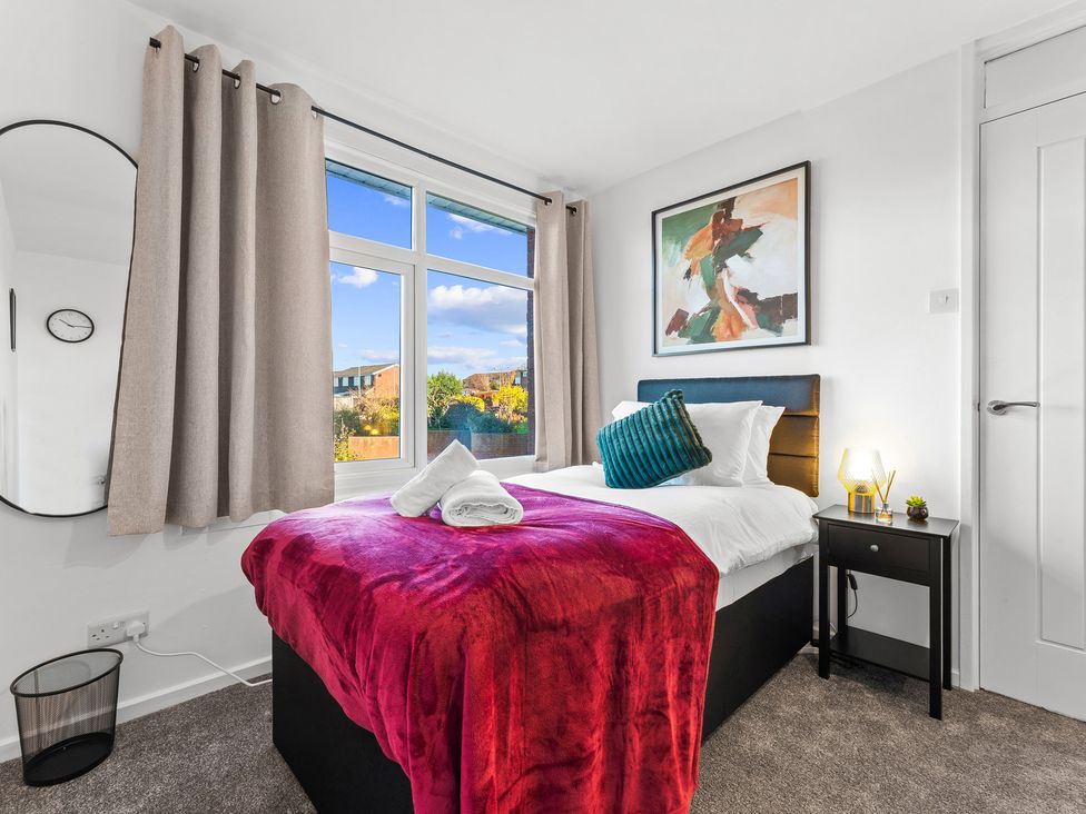 A bedroom with a bed and side table at Edison House Stafford