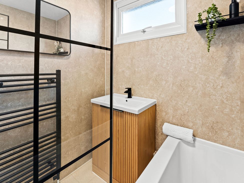 A bathroom with a shower, sink, and towel rack at Edison House Stafford