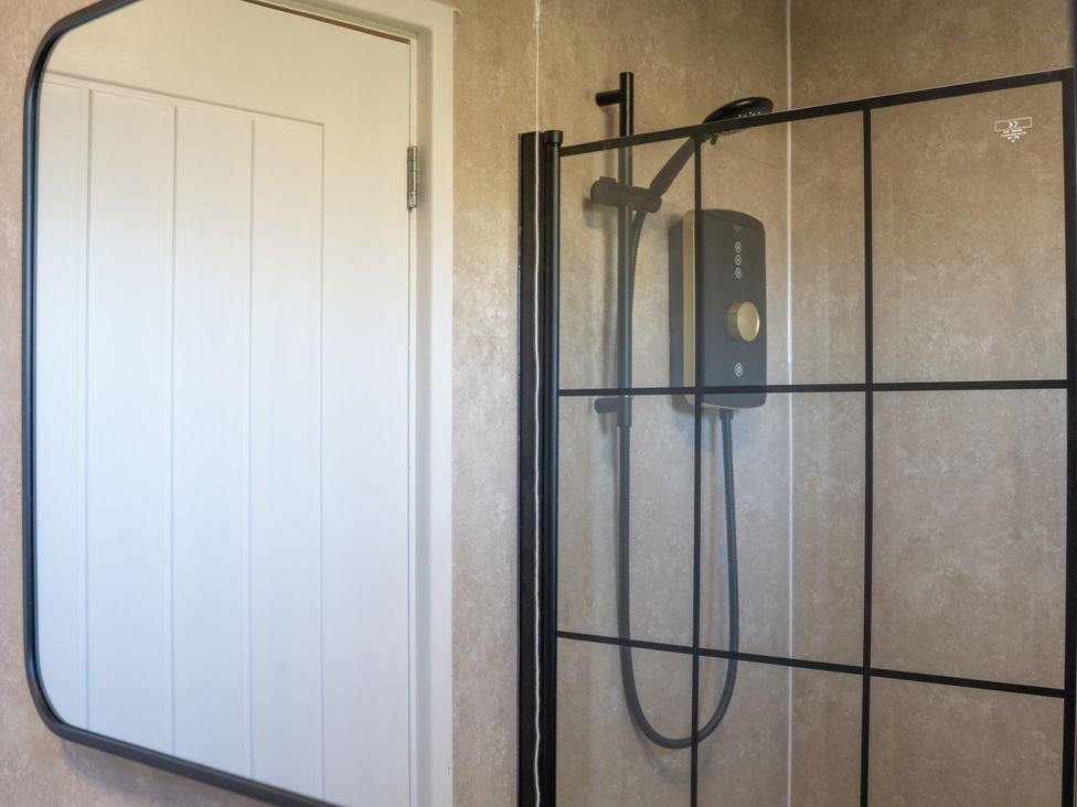 A bathroom with a shower and a mirror at Edison House Stafford