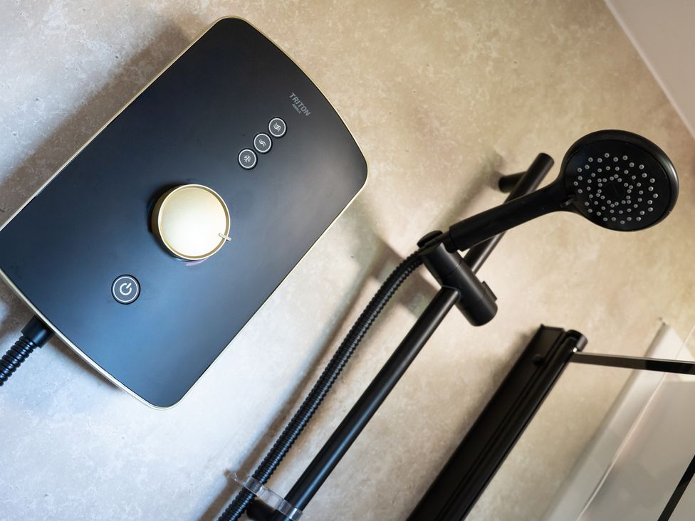 A shower unit with a head and control knobs at Edison House in Stafford