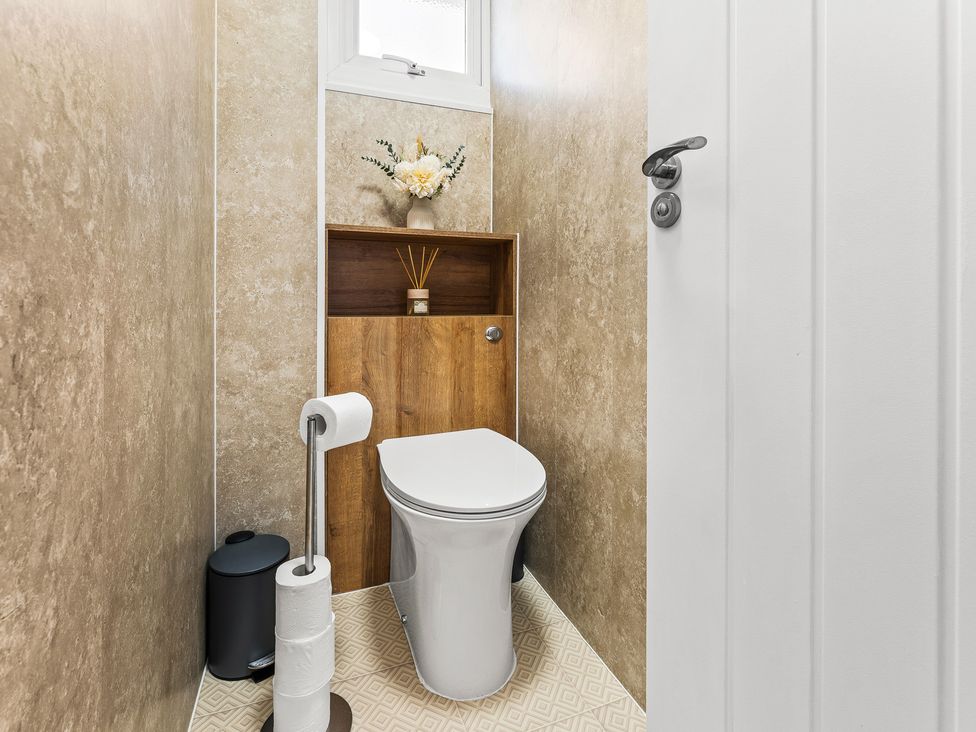 A bathroom with a toilet and a shelf featuring flowers at Edison House Stafford