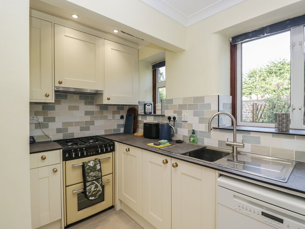 A kitchen with cabinets, a stove, sink and dishwasher at Throstlegarth in Milnthorpe