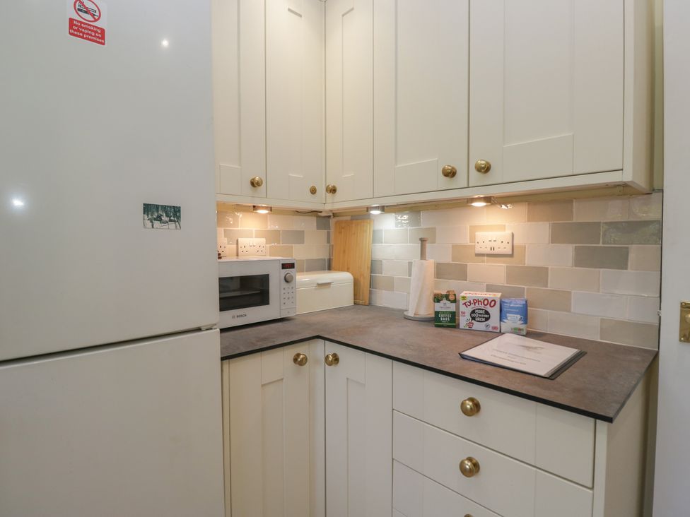 A kitchen with cabinets, a microwave, and a refrigerator at Throstlegarth in Milnthorpe